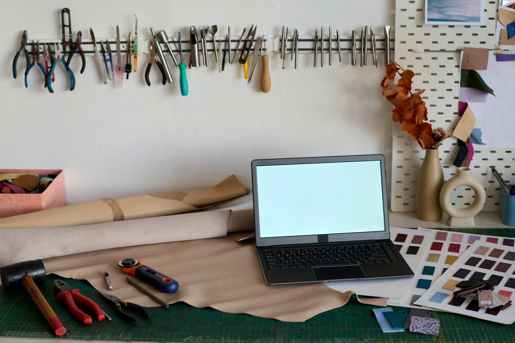 Studio artigiano con attrezzature per ricamo e laptop